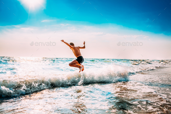 Boy Having Fun And Jumping In Sea Ocean Waves. Jump Accompanied - Stock Photo - Images
