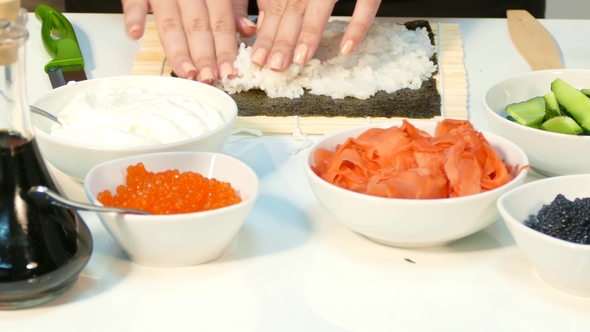 Chef Hands Kneading Rice on the Nori Sheet on the Kitchen Table