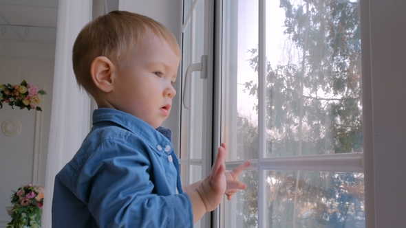 Pensive Little Boy Looking Through Window