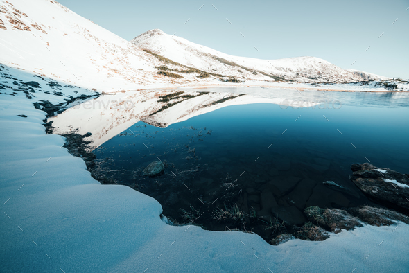 Frozen mountain lake with blue ice - Stock Photo - Images