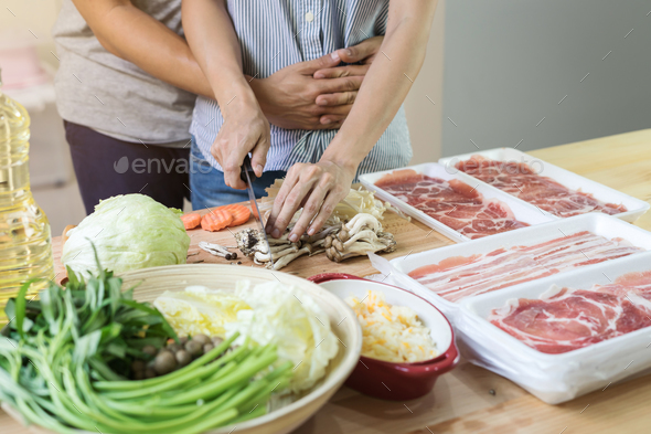 Young asian couple cutting vegetable in the kitchen Stock Photo by kitzstocker