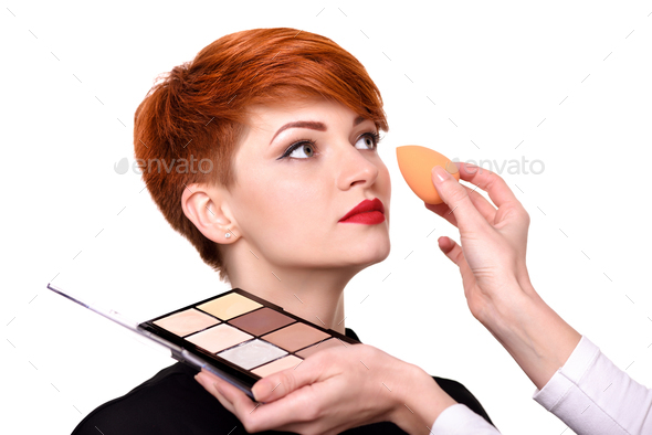 Makeup artist applying foundation on young woman's face using sp - Stock Photo - Images