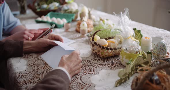 Happy Easter - Grandfather and Granddaughter Writing Easter Cards with Greetings. alt