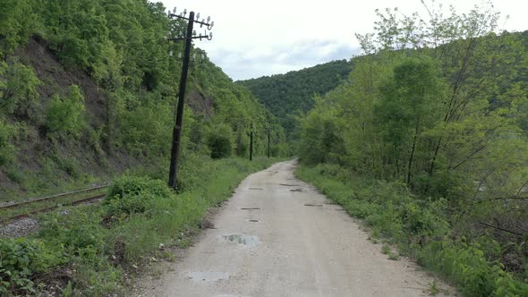 Above parallel railway track  muddy road with puddles 4K aerial video alt