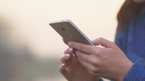Woman Is Using a Mobile Phone at Sunset