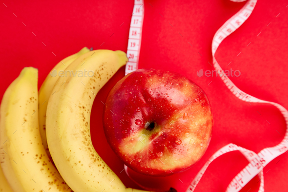 Measuring tape wrapped around a red apple and banana - Stock Photo - Images