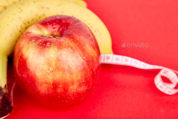 Measuring tape wrapped around a red apple and banana - Stock Photo - Images