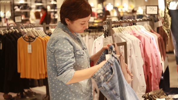 The Girl Chooses Clothes in the Store