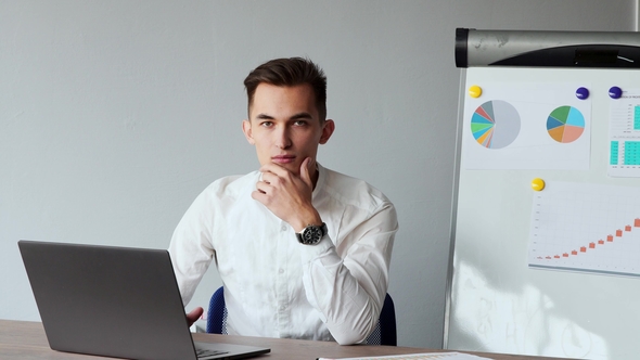 European Male Sitting at a Laptop in the Office with a White Shirt alt