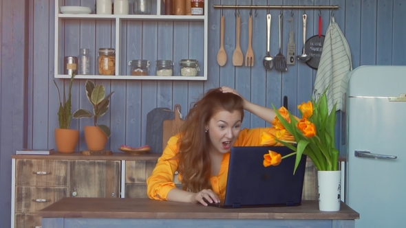 Woman with Arms Raised Using Laptop in the Kitchen