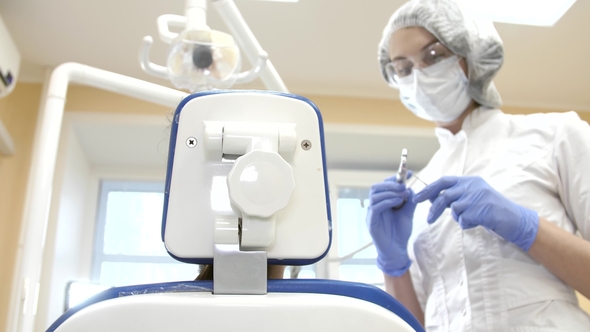 Dentist at Work in Dental Unit with a Girl Lying Client