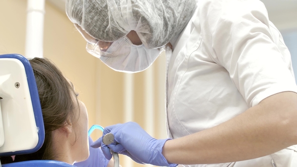 Dentist at Work in Dental Unit. Doctor in Special Mask and Glasses