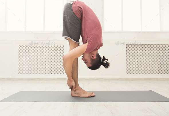 Sporty man doing Standing Forward Bend Stock Photo by Milkosx | PhotoDune