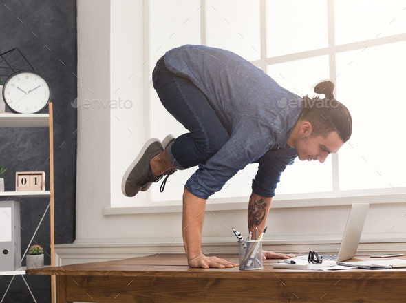 Flexible man practicing yoga at workplace Stock Photo by Milkosx | PhotoDune