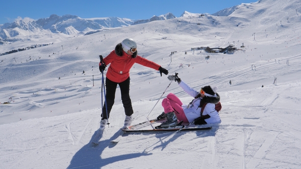 Woman Skier Helps The Other To Rise To Her Feet After Falling On The Ski Slope