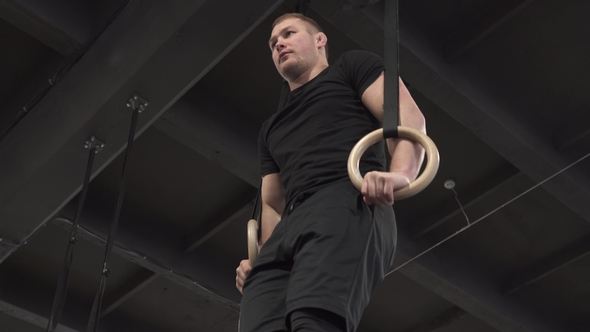 Male Athlete Doing Rings Muscle Ups Exercise in Gym