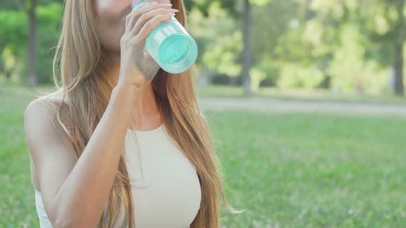 Healthy Fit Woman Drinking Water While Doing Yoga in the Park