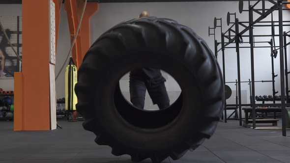 Fitness Man Doing Big Tire Flips Exercise in Gym