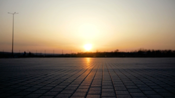 Two Guys Ride on Bicycles towards the Sunset on a Large Area