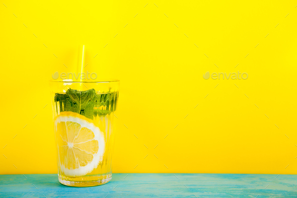 Glass with organic and fresh lemonade over yellow background Stock Photo by DC_Studio