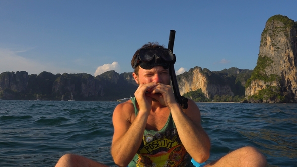 Man Playing Harp on Kayak in the Open Sea in Mask and Tube for Diving or Snorkeling