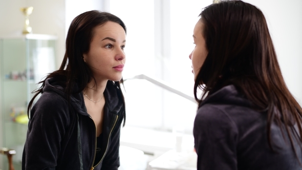 Young Beautiful Girl Looks at Herself in Mirror