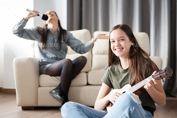 Two sisters having fun in the living room Stock Photo by DC_Studio