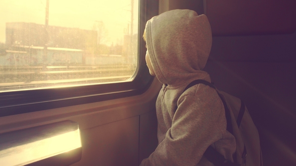 A Boy Is Riding in a Train Looking Out the Window