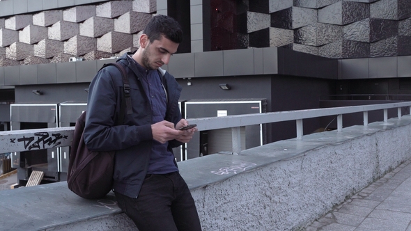 Young Handsome Arabic Man Using Smartphone in City alt