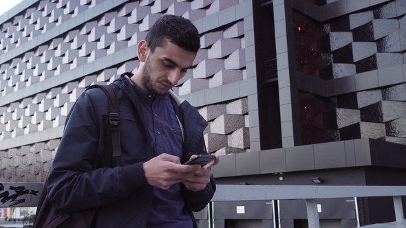 Young Happy Middle Eastern Man Using a Smartphone and Smiling in City