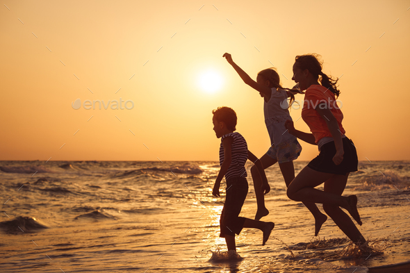 Happy children playing on the beach at the sunset time. - Stock Photo - Images