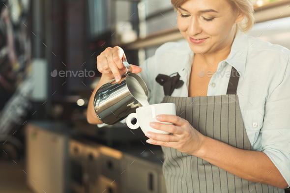 Experienced barista pouring milk to cappuccino cup Stock Photo by Milkosx