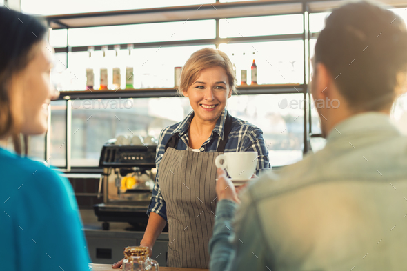 Experienced smiling barista making coffee to customers Stock Photo by Milkosx