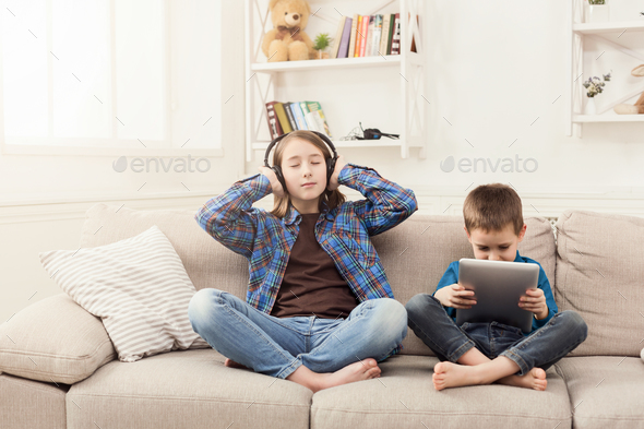 Two kids listening music on couch at home Stock Photo by Milkosx | PhotoDune