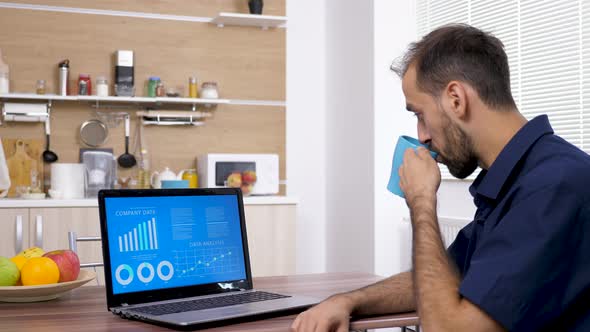 Young Businessman Drinks Coffee and Looks at Data and Chart Analysis alt
