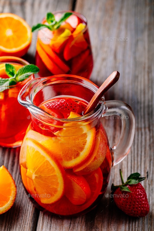 Homemade red wine sangria with orange, apple, strawberry and ice in pitcher and glass Stock