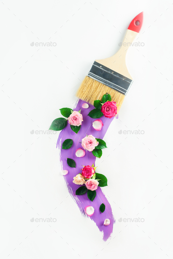 Creative spring transfiguration concept with flowers, paint brush and a swoosh of lavender color