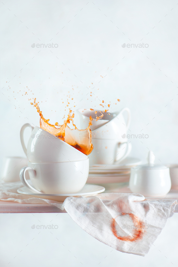 Coffee cup with a dynamic splash on a kitchen shelf with porcelain dishes, saucers, cups. White on - Stock Photo - Images