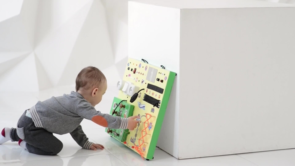 Little Baby Boy Intently Playing with Busy Board alt