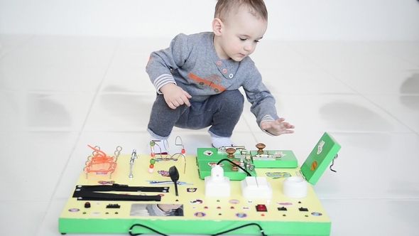 Little Baby Boy Intently Playing with Busy Board