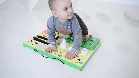 Little Baby Boy Intently Playing with Busy Board alt