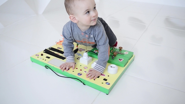 Little Baby Boy Intently Playing with Busy Board