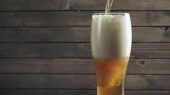 Beer Poured in Glass on Wood Background