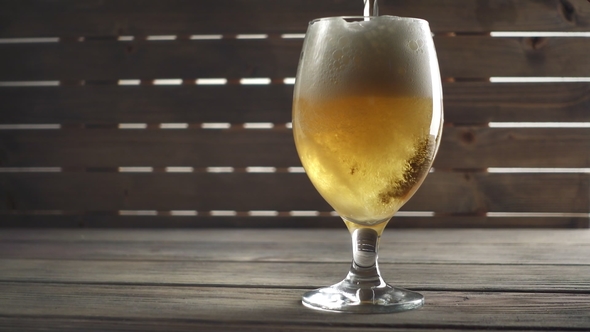 Beer Poured in Glass on Wood Background.