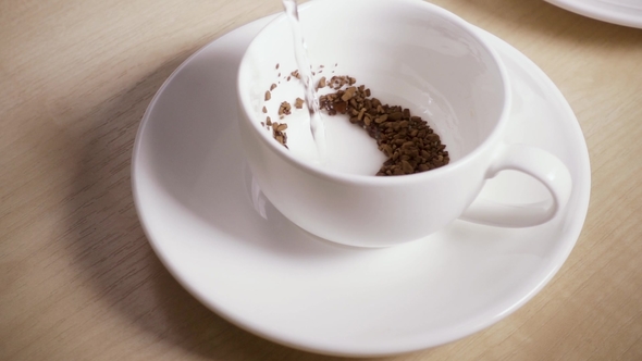 Water Is Poured Into a Mug with Instant Coffee