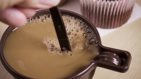 Woman Stirs Coffee with Cream in a Mug