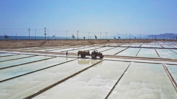 Tractor with Cistern Drives among Vast Salt Fields alt