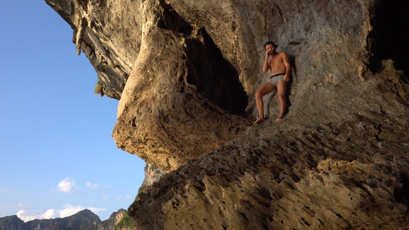 Brave Adventurist Man Is Playing Hapr Barefoot on the Slope of Sharp Island Limestone Cave in the