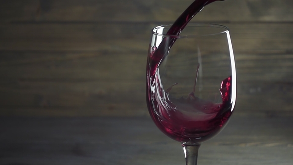 Red Wine Poured Into Glass Against Wooden Background