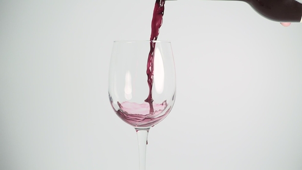 Pouring Red Wine Into the Glass Against White Background.